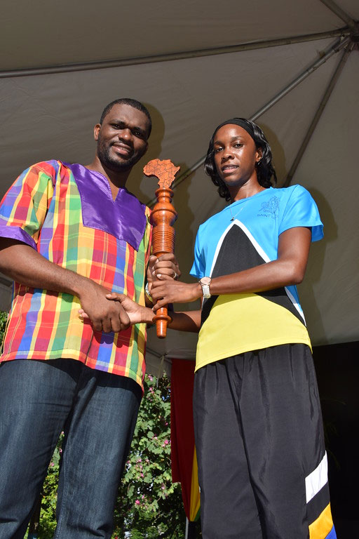 Olympic High-jumper Levern Spencer (in Olympic national flag gear) handed the CARICOM Reparations Baton to Dean of the CARICOM Youth Ambassadors Charde Desir, during the Reparations and Kwéyol Youth Rally held after the October 29 CARICOM Reparations Baton Relay.